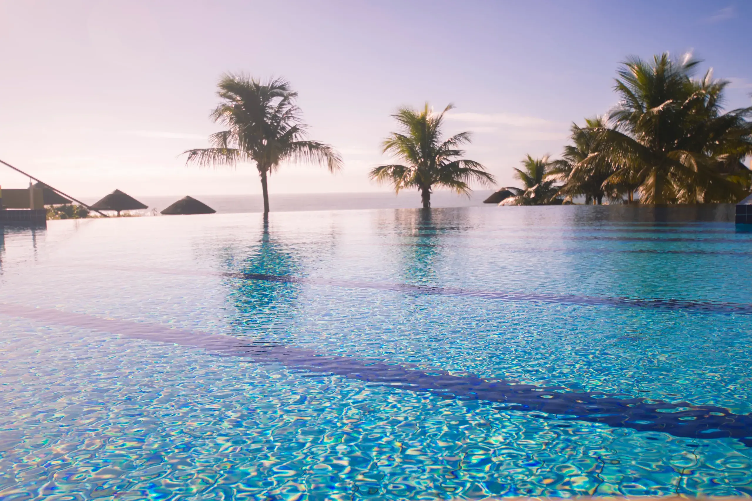 Piscina de borda infinita do Costao do Santinho ao entardecer, com o mar ao fundo